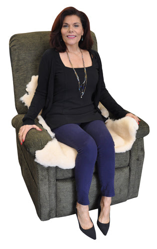 Woman sitting on a recliner chair with Natural Sheepskin Pad Large Size draped over the seat and armrests.
