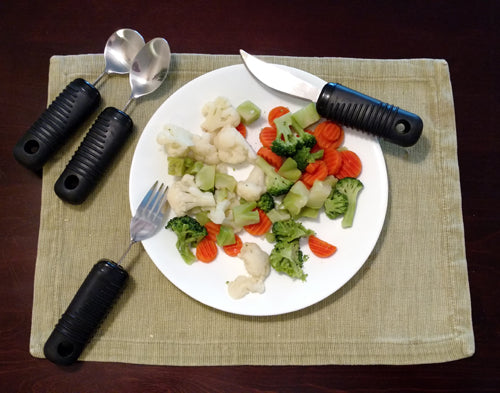 Make Eating Easier Big Grip Utensil Set Blue Jay Brand with ribbed handles and stainless steel utensils on a plate of vegetables.