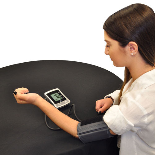Woman using Full Automatic Blood Pressure w/4 AA Blue Jay Brand digital blood pressure monitor on black table.