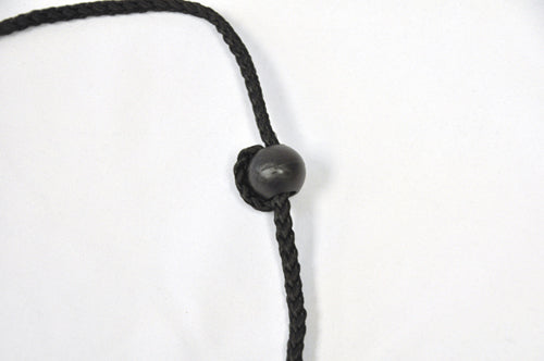 Close-up of black braided cord with a smooth black plastic bead knotted onto it against white background