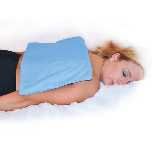 Woman lying face down on bed with a blue heating pad covering her upper back and shoulders