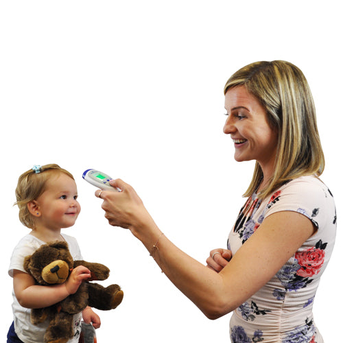 Woman smiling while using a digital infrared thermometer to check the temperature of a toddler holding a teddy bear