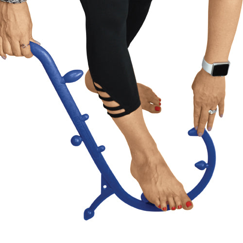 Person using a curved blue massage tool with knobs to roll and stretch the soles of bare feet against white background